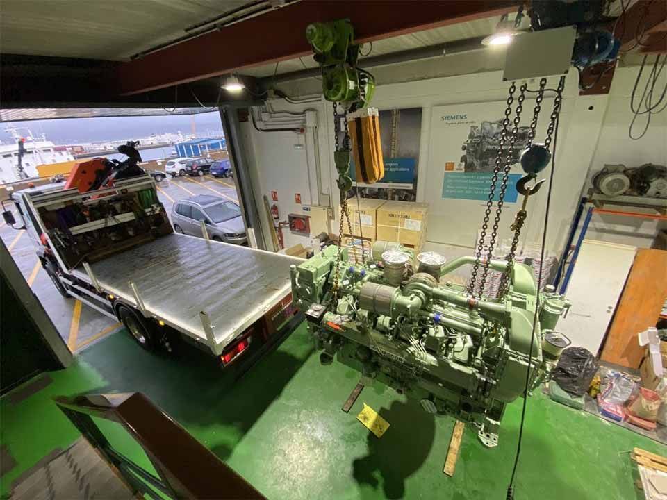 Un motor de gran tamaño es levantado por una grúa en un garaje.