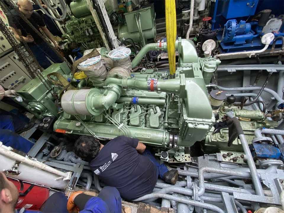 Un grupo de hombres está trabajando en un motor grande en un barco.