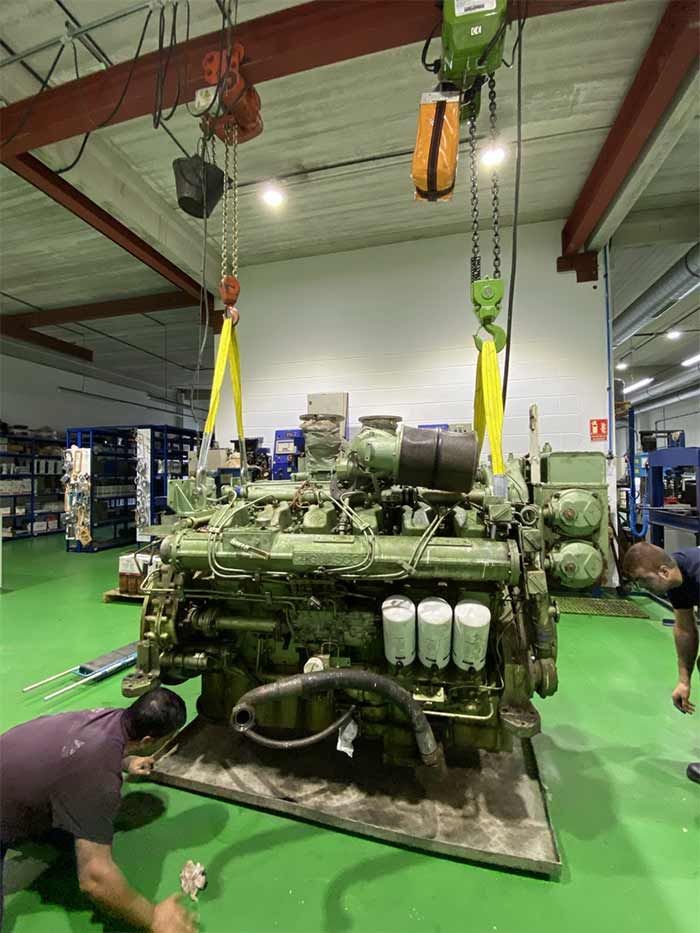 Un hombre está trabajando en un motor grande en un almacén.