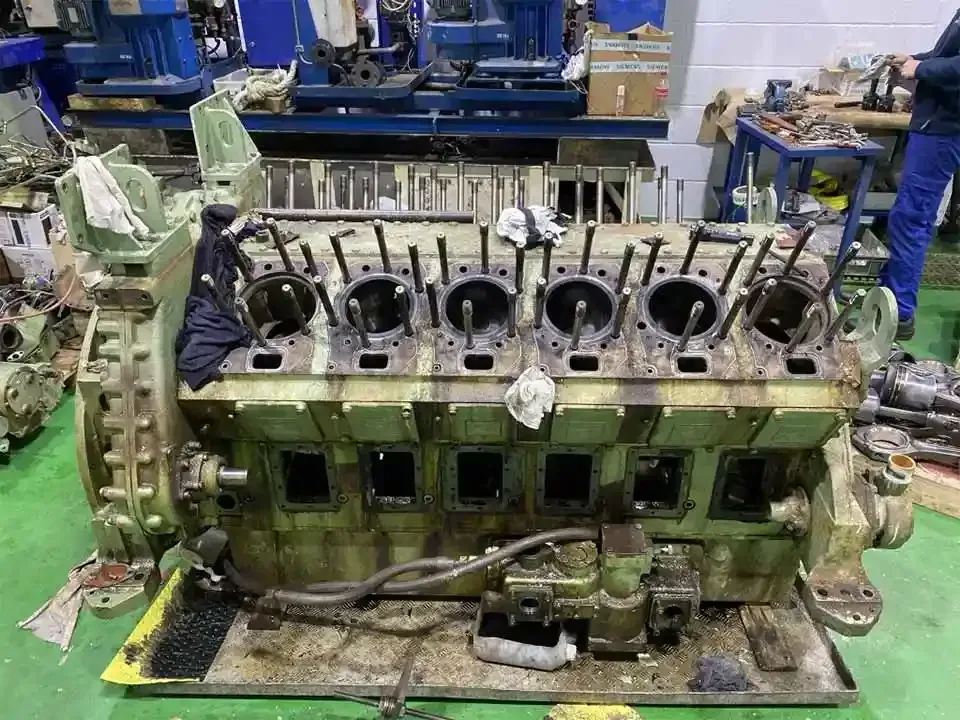 Un gran motor está sobre una mesa verde en una fábrica.