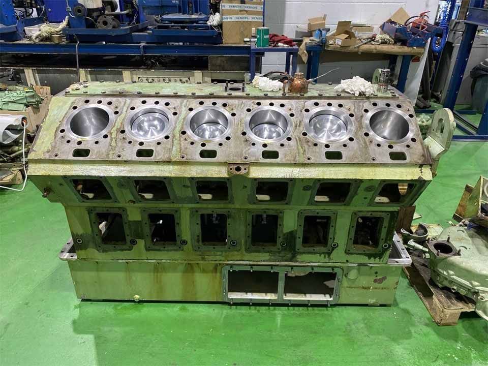 Un gran bloque de motor se encuentra sobre un piso verde en una fábrica.