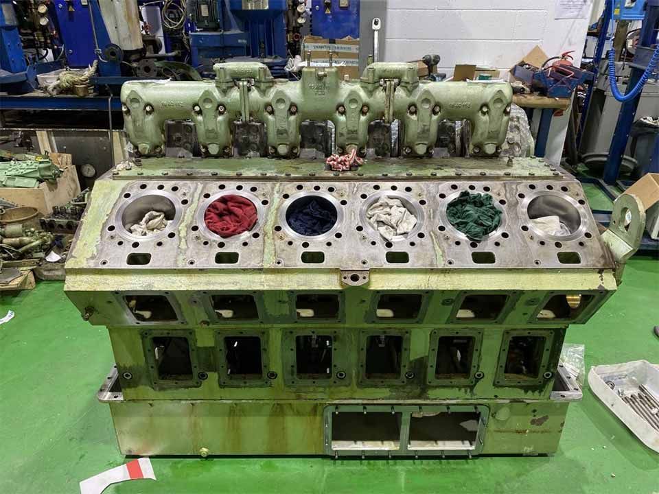 Un gran motor se encuentra sobre un suelo verde en una fábrica.