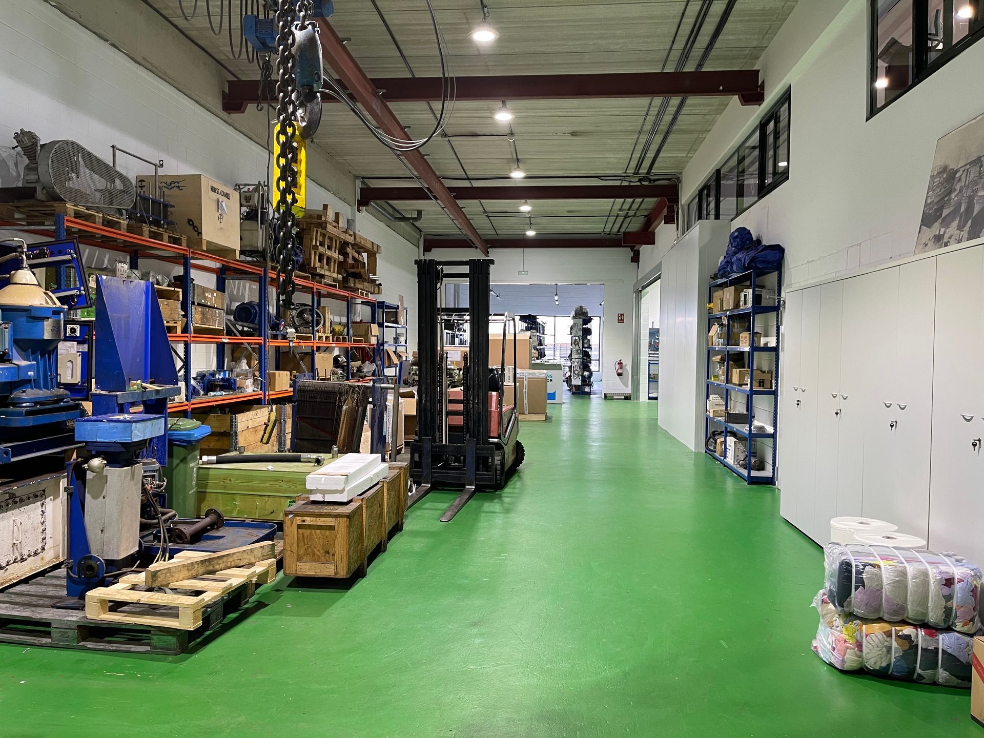 Un gran almacén con suelos verdes y mucha maquinaria.