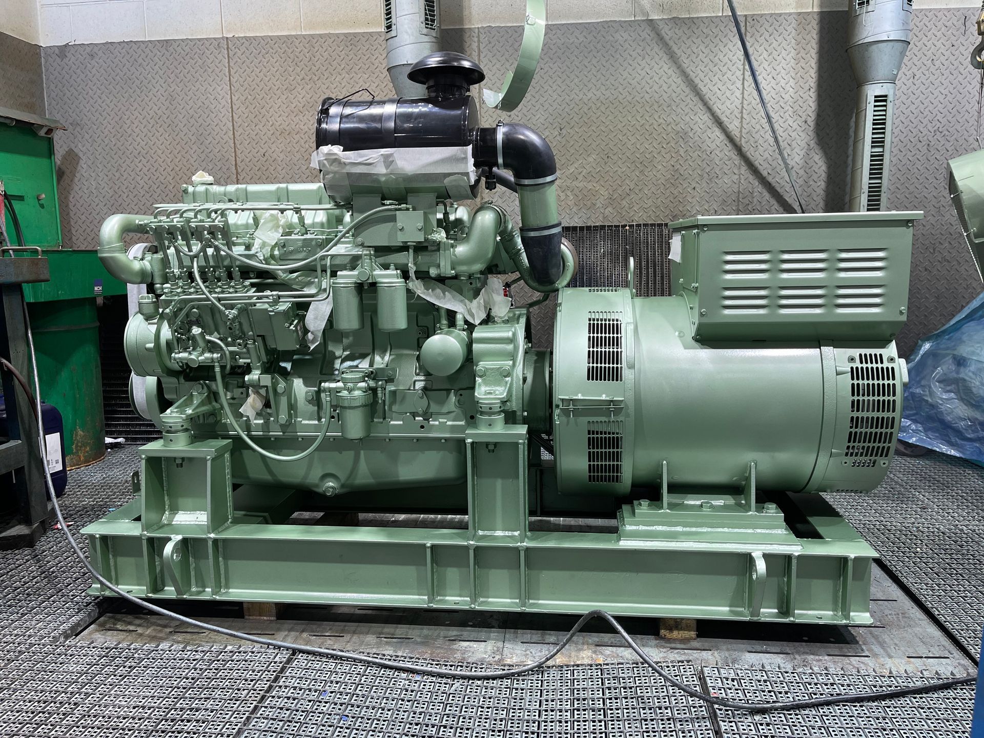 Un generador diésel verde está en el suelo, en una habitación.