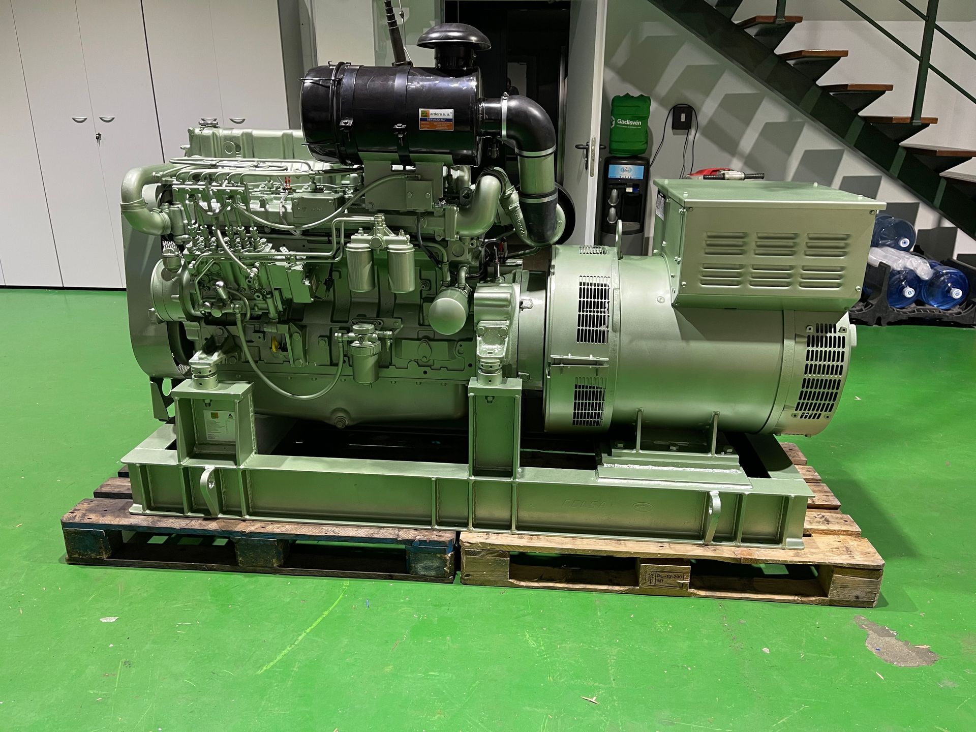 Un generador diésel está sobre una paleta de madera en una habitación.