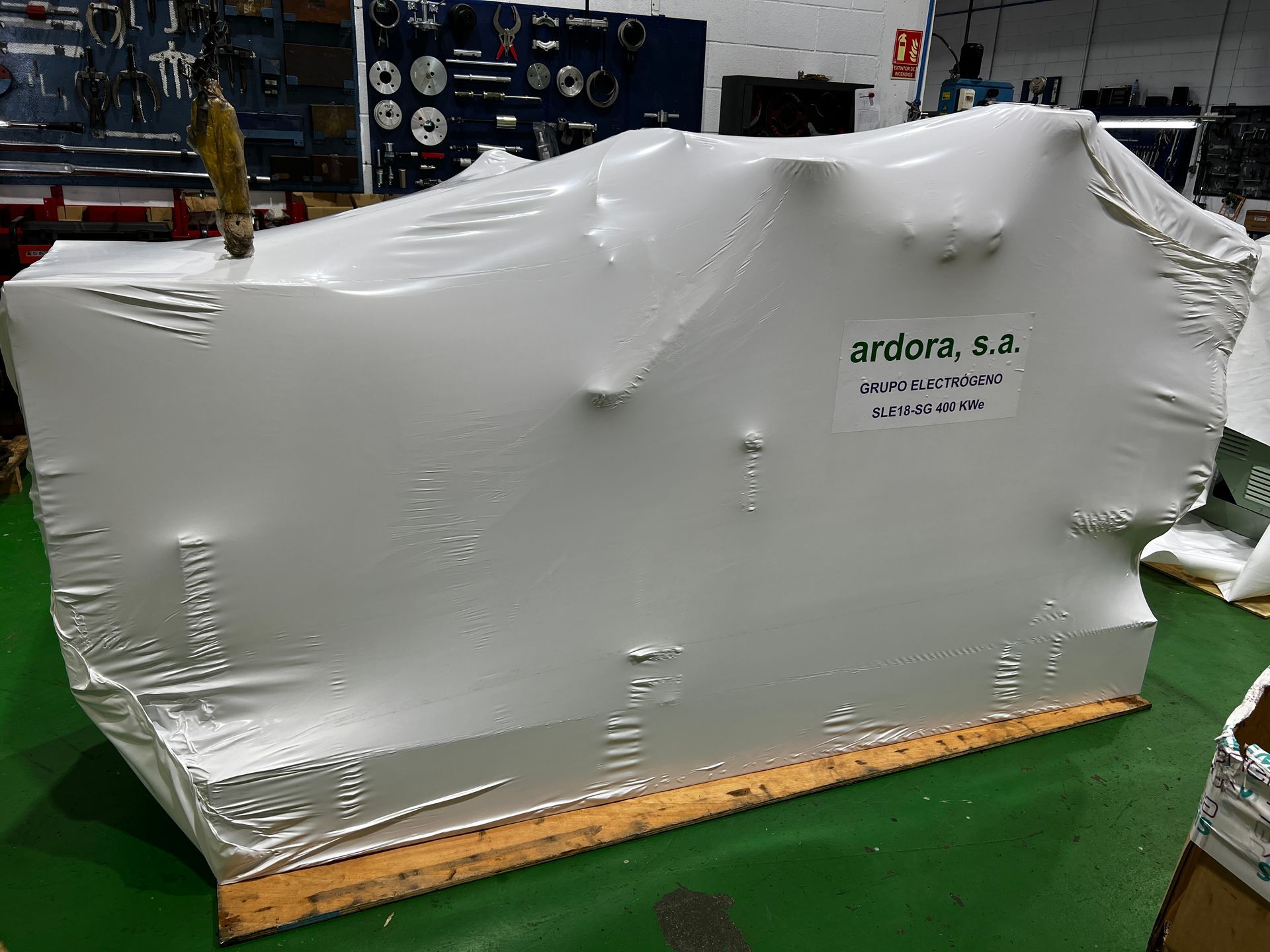 Un objeto grande envuelto en plástico se encuentra sobre una paleta de madera.