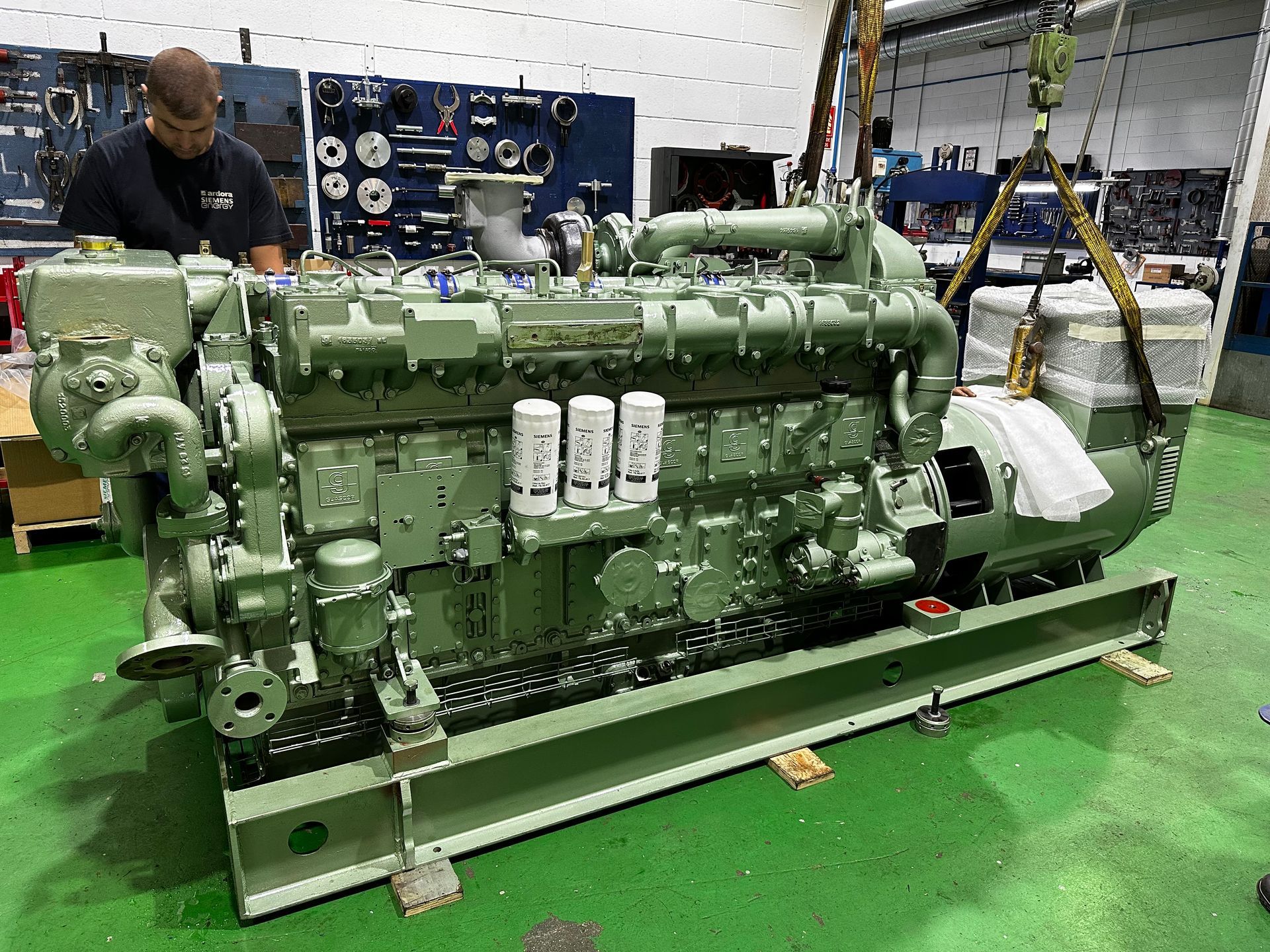 Un hombre está trabajando en un motor grande en una fábrica.