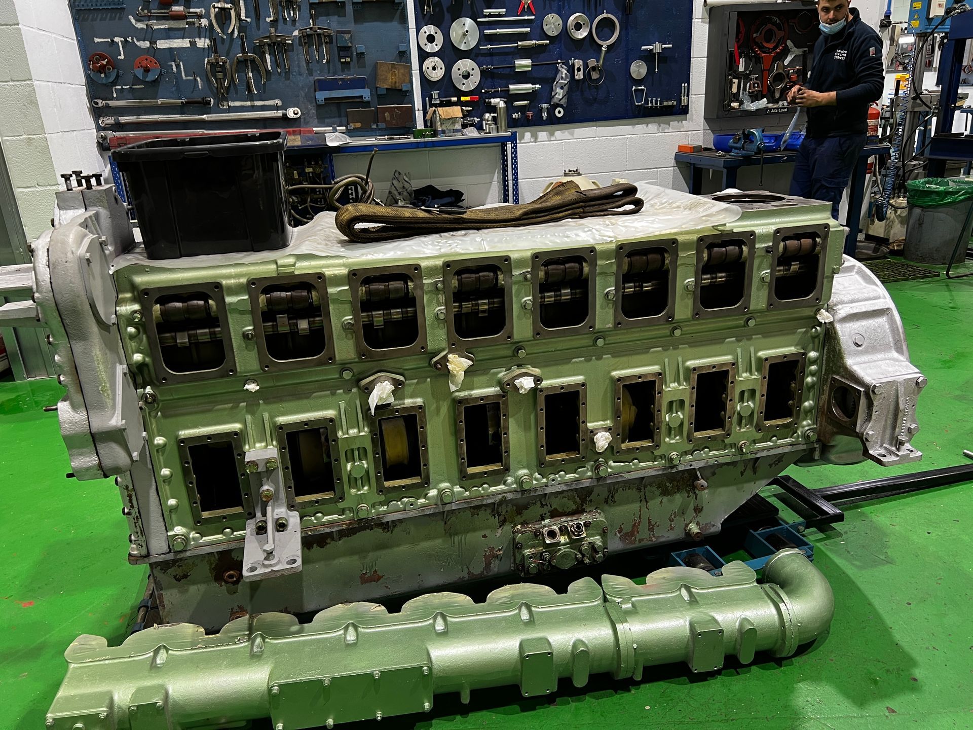 Un motor de gran tamaño se encuentra sobre un suelo verde en un taller.