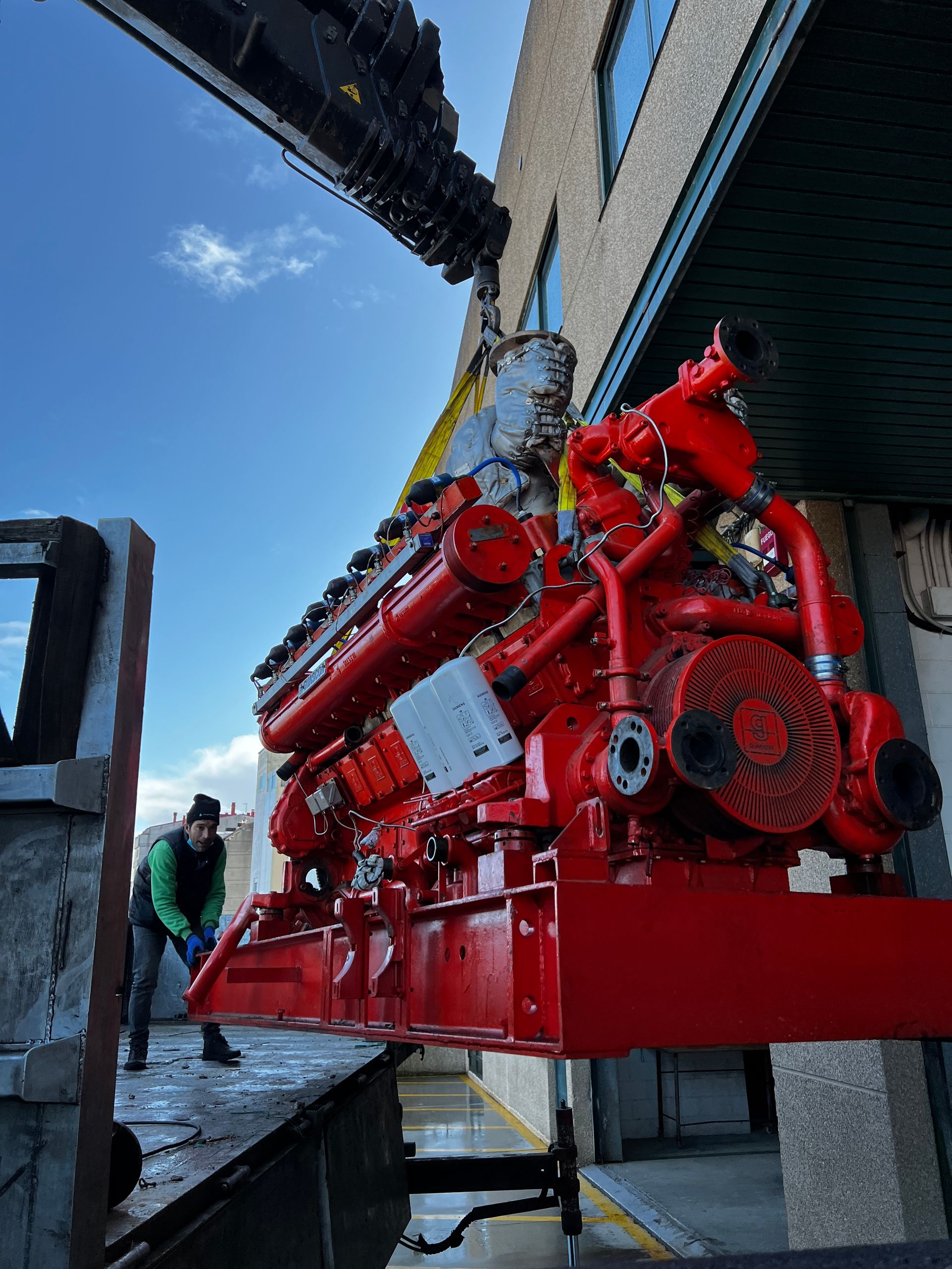 Un gran motor rojo está siendo levantado por una grúa.