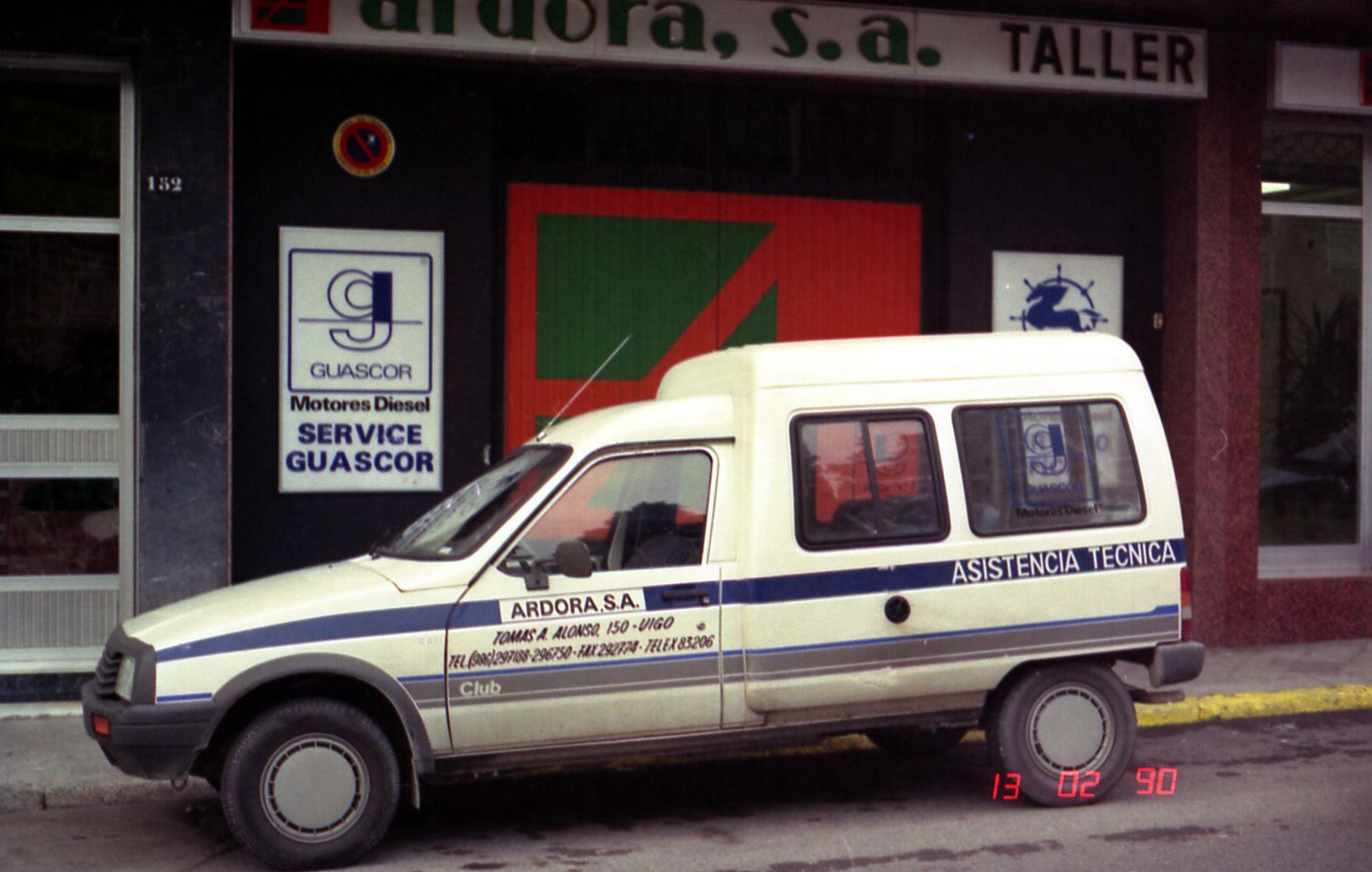 Una camioneta blanca está estacionada frente a un edificio más alto.