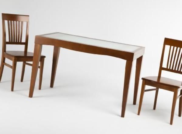 Mesa de madera marrón flanqueada por dos sillas a juego sobre un fondo blanco