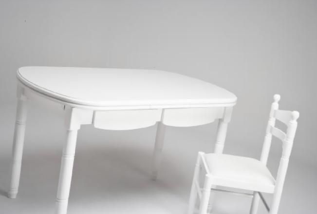 Mesa y silla de madera blanca sobre un fondo gris claro de estudio