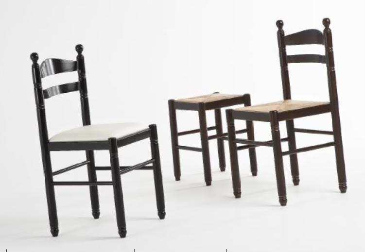 Tres sillas de madera oscura y una mesita a juego sobre un fondo blanco
