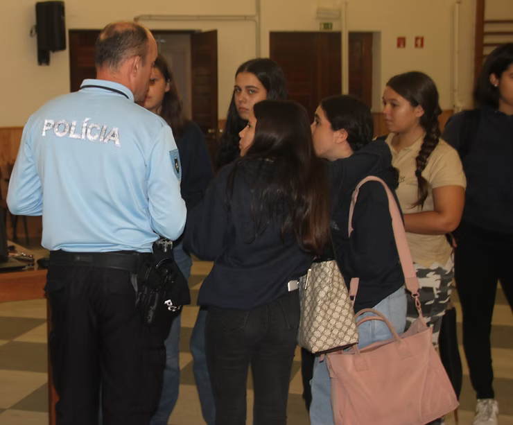Policial conversando com um pequeno grupo de pessoas em ambiente fechado.