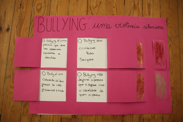Cartaz rosa contra o bullying com quatro mensagens escritas à mão e a palavra