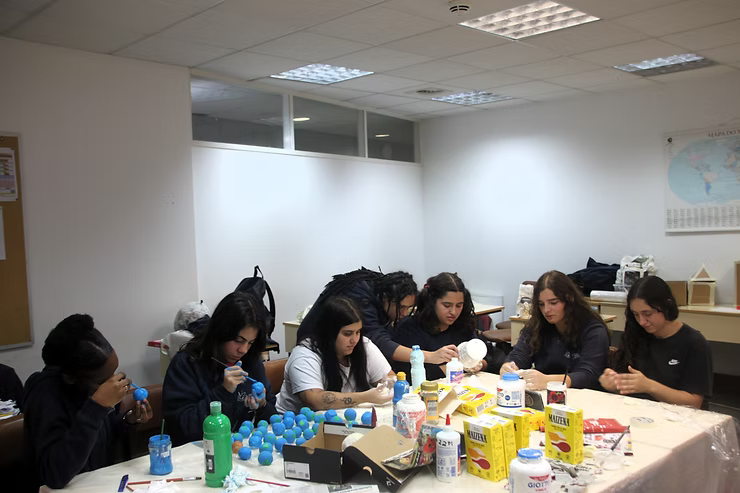 Pessoas sentadas ao redor de uma mesa em uma sala iluminada, comendo e conversando durante uma refeição.