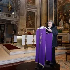 Pessoa discursando em um púlpito roxo no interior de uma igreja.