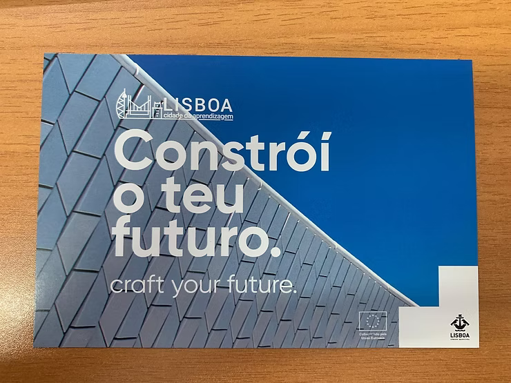 Pôster azul com um prédio moderno e o texto “Constrói o teu futuro. Craft your future.”