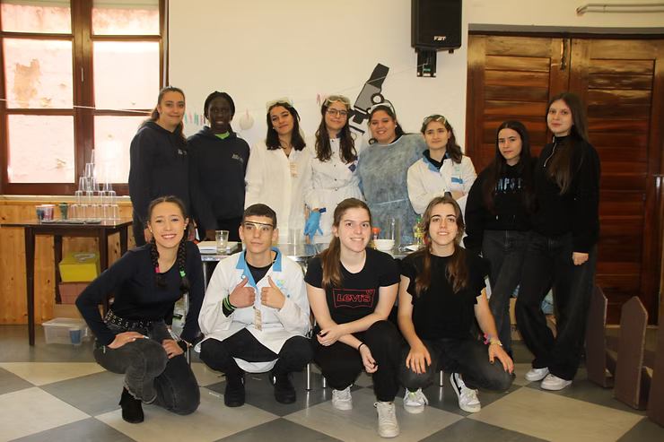 Grupo de pessoas posando em um ambiente interno, em frente a uma janela e parede de madeira, sorrindo para uma foto de equipe.