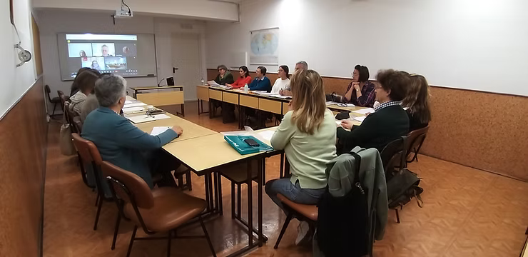 Pessoas sentadas ao redor de uma mesa de conferência em uma sala de reuniões, voltadas para a frente.