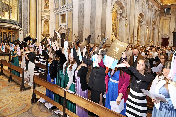 Pessoas em um corredor da igreja levantam livros e papéis durante uma cerimônia.