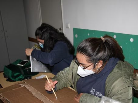 Dois alunos mascarados escrevendo em carteiras numa sala de aula.