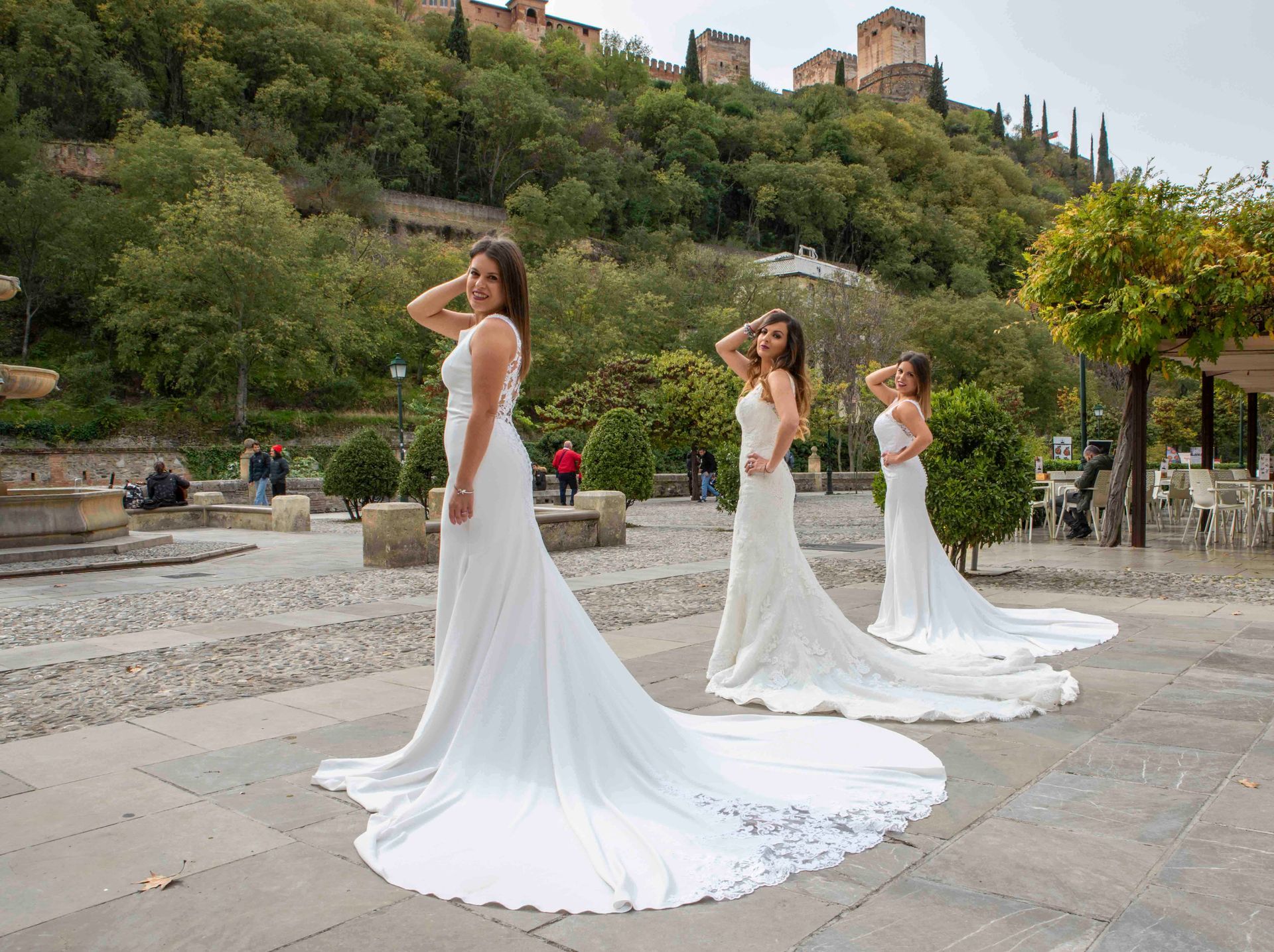 Tres mujeres con vestidos blancos están paradas una al lado de la otra en una acera.