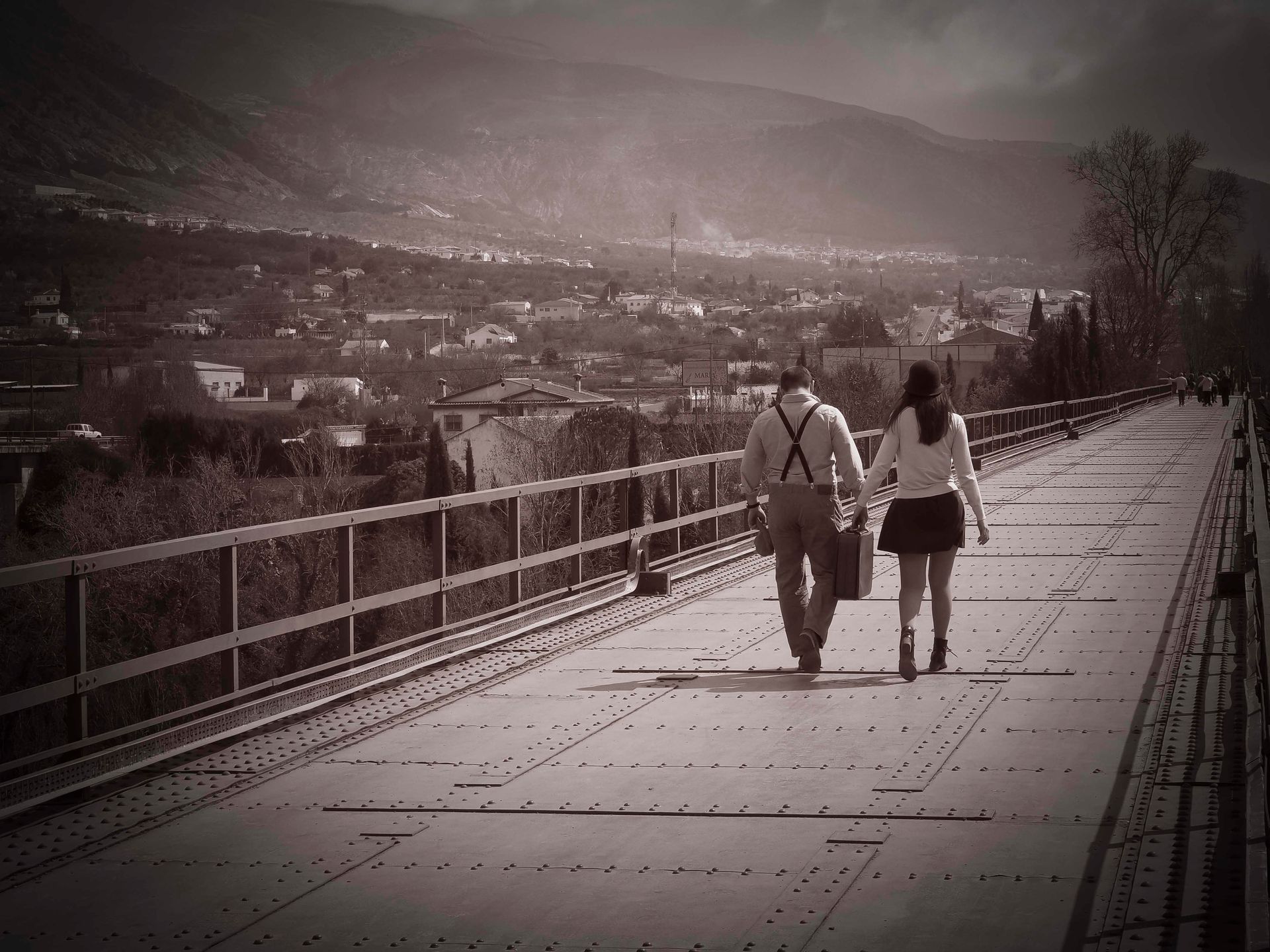 Un hombre y una mujer caminan por un puente tomados de la mano.
