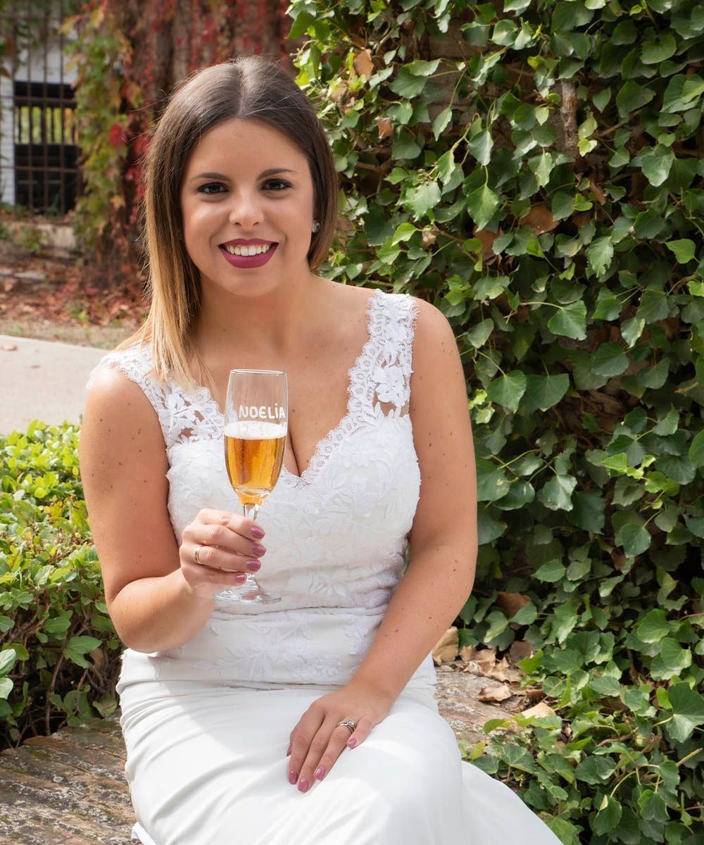 Una mujer con un vestido blanco sostiene un vaso de cerveza.