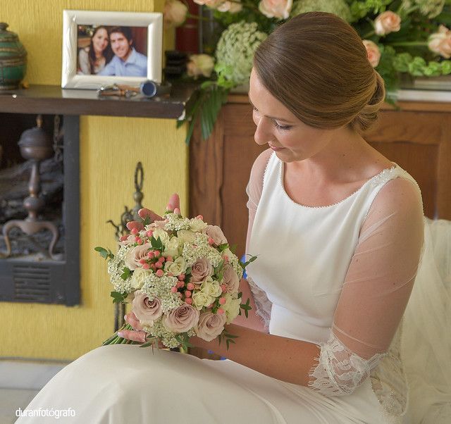 Una mujer con un vestido blanco sostiene un ramo de flores.