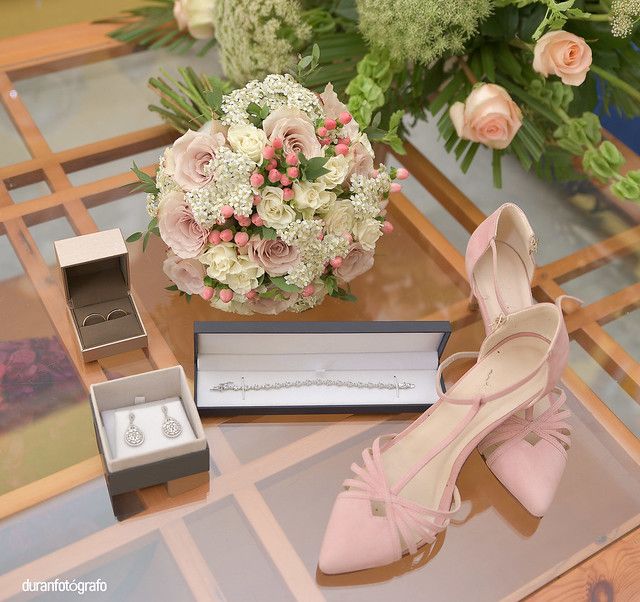 Una mesa con un ramo de flores y un par de zapatos.