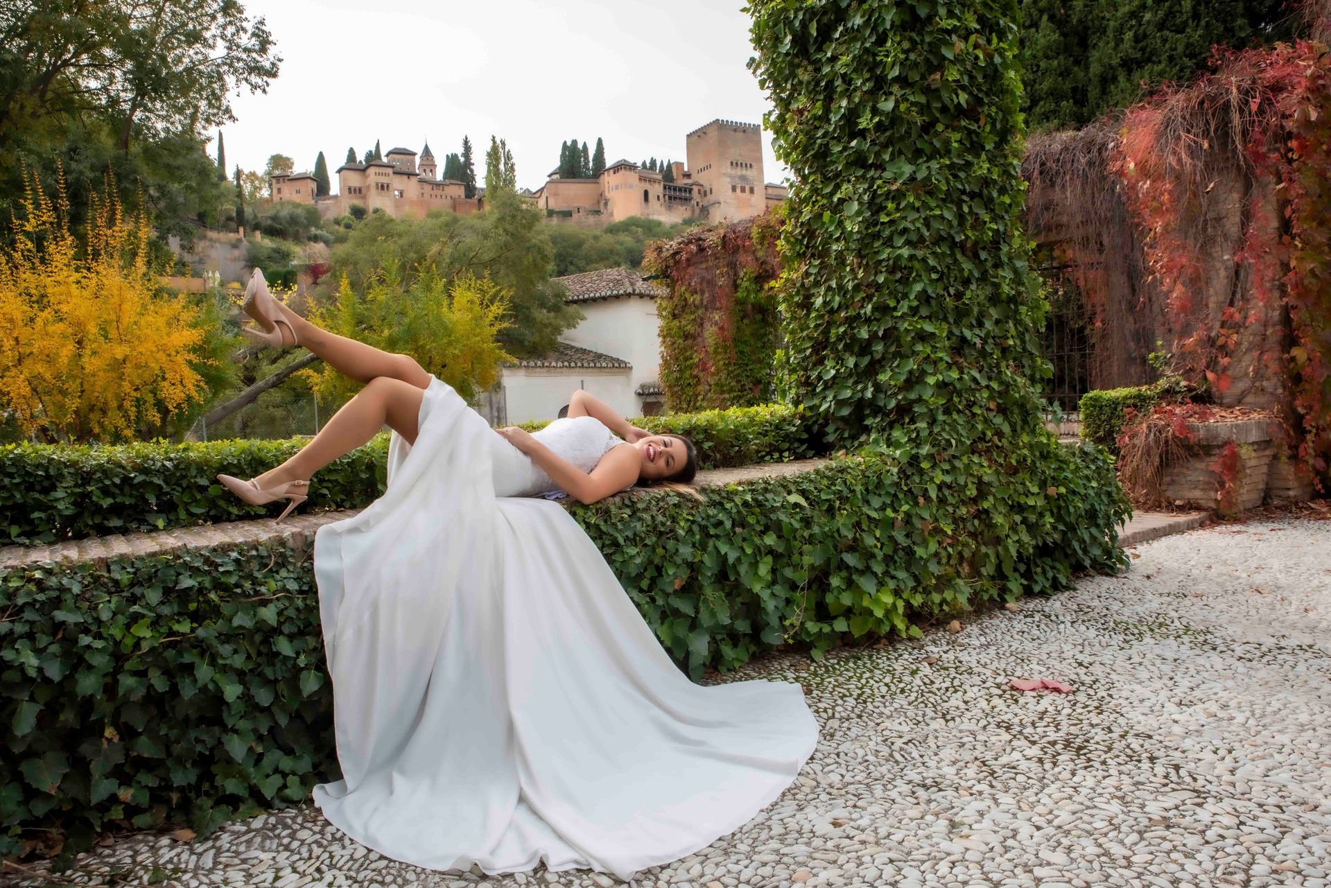 Una mujer con un vestido de novia está tumbada en el suelo en un parque.