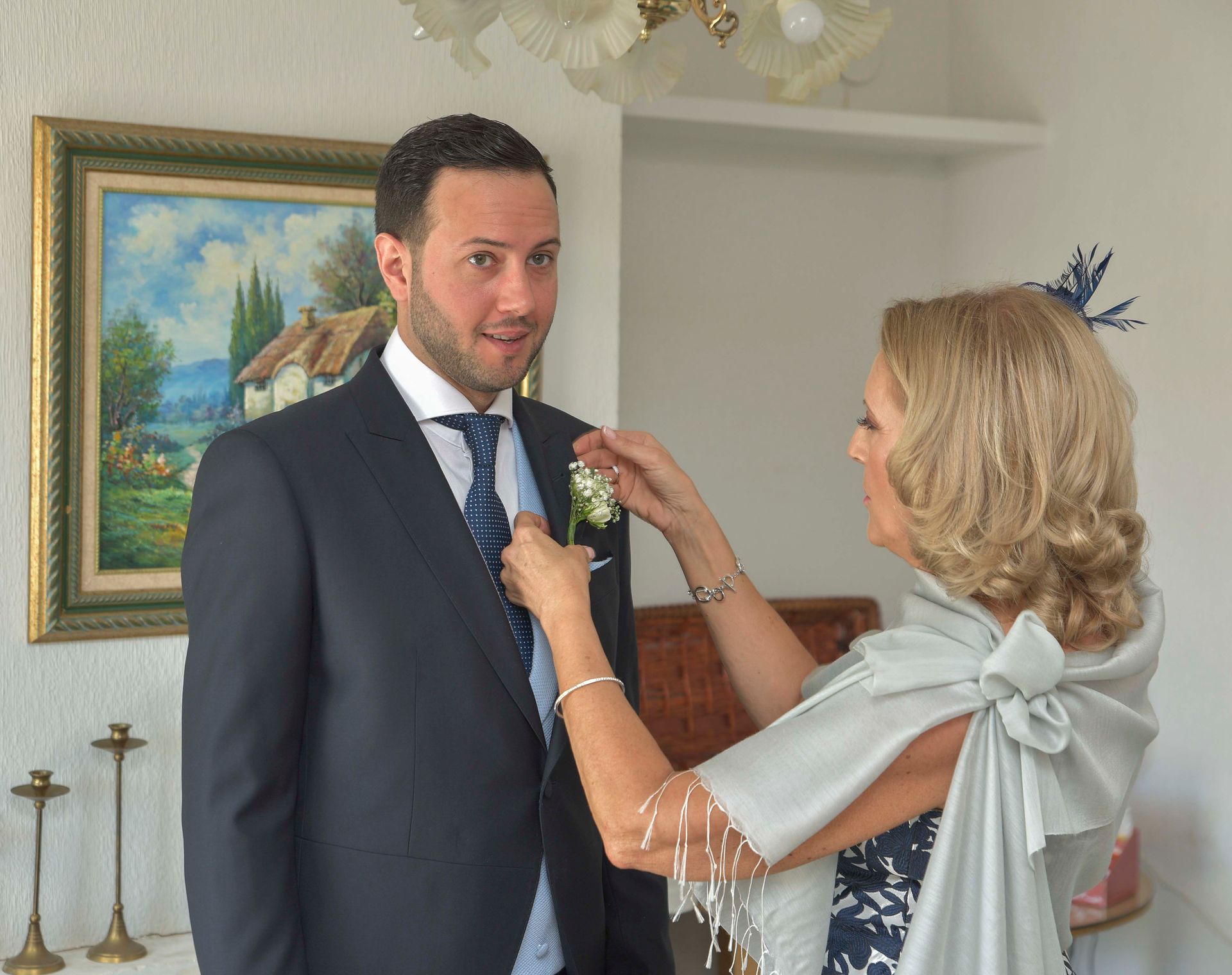Una mujer está ayudando a un hombre con su traje y corbata.
