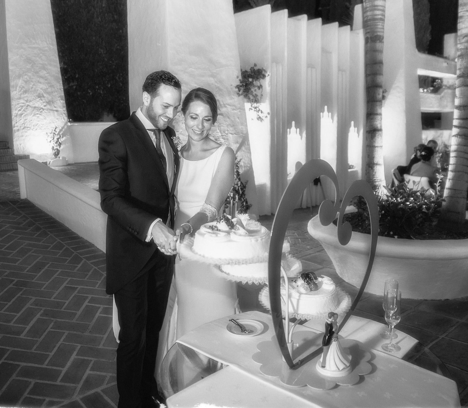 Una foto en blanco y negro de una novia y un novio cortando su pastel de bodas.