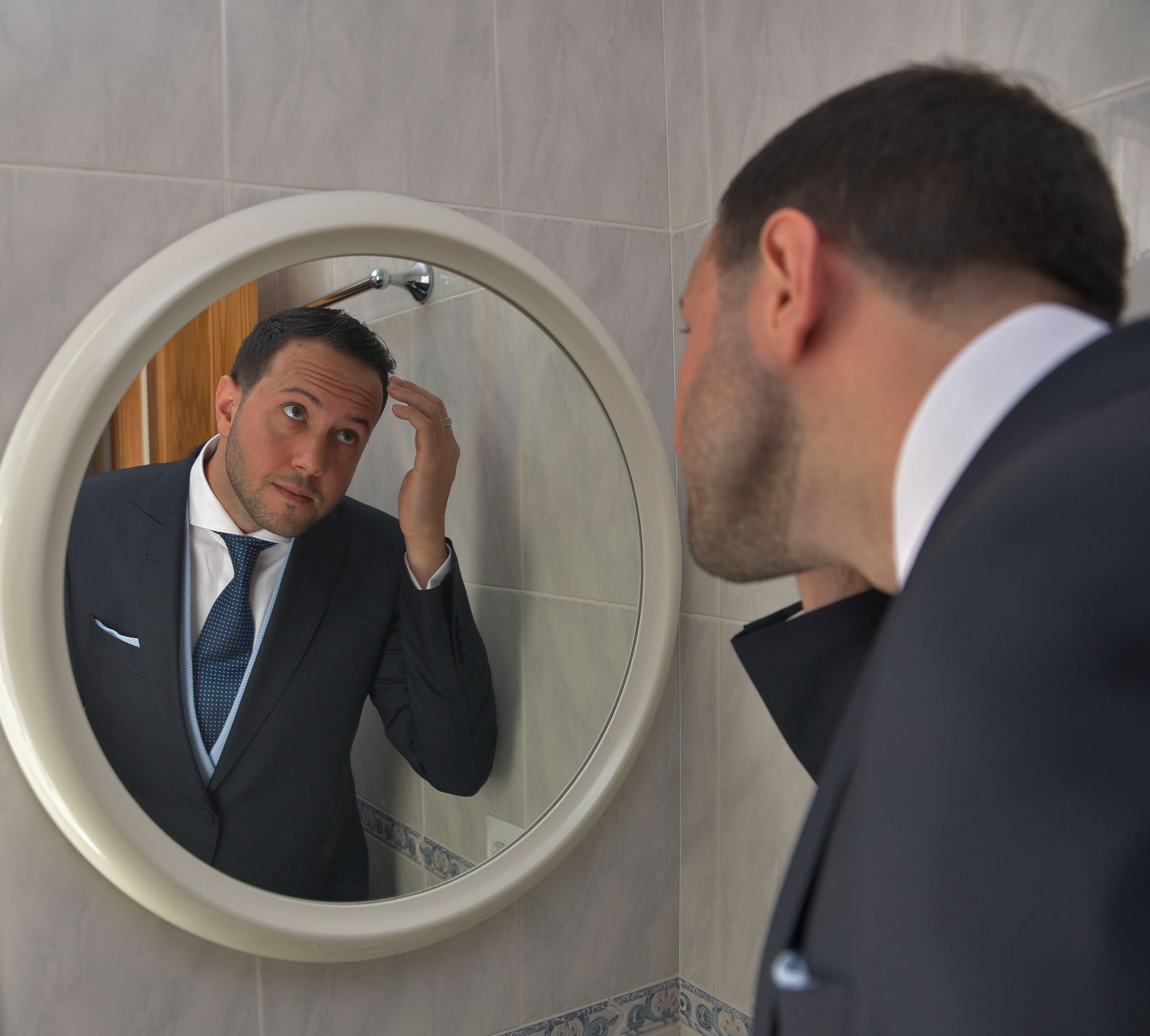 Un hombre con traje mira su reflejo en un espejo.