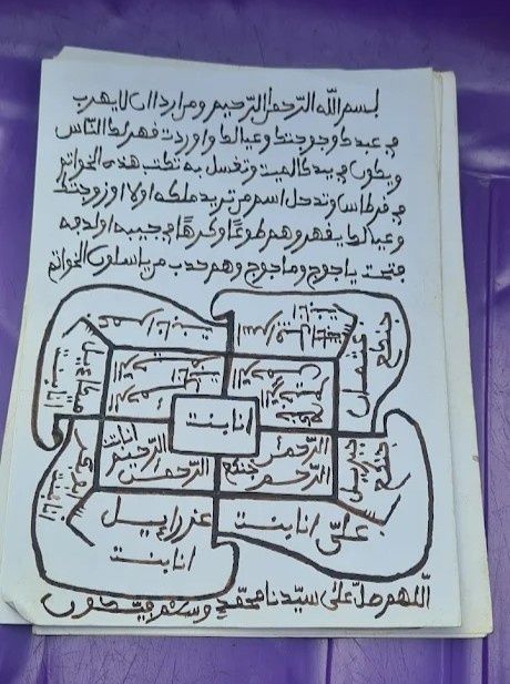 Mujer con ropa deportiva roja levanta los brazos al cielo, con los ojos cerrados. Vista al mar, día soleado.