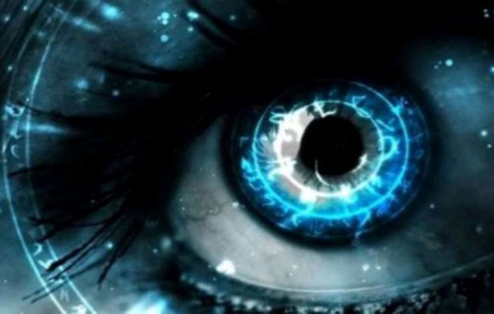 Hombre abraza a persona con camisa naranja, sonriendo ampliamente. Al aire libre, con palmeras al fondo.