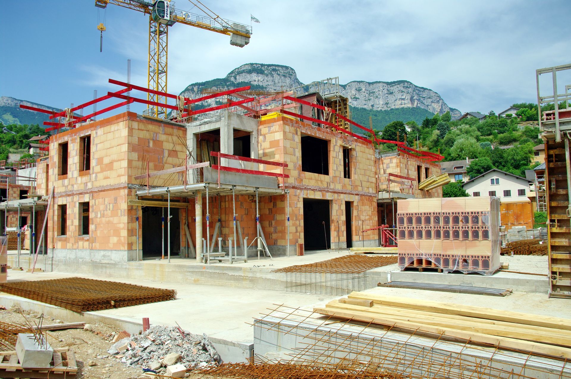 Maisons en briques partiellement construites sur un chantier avec échafaudages et grue.