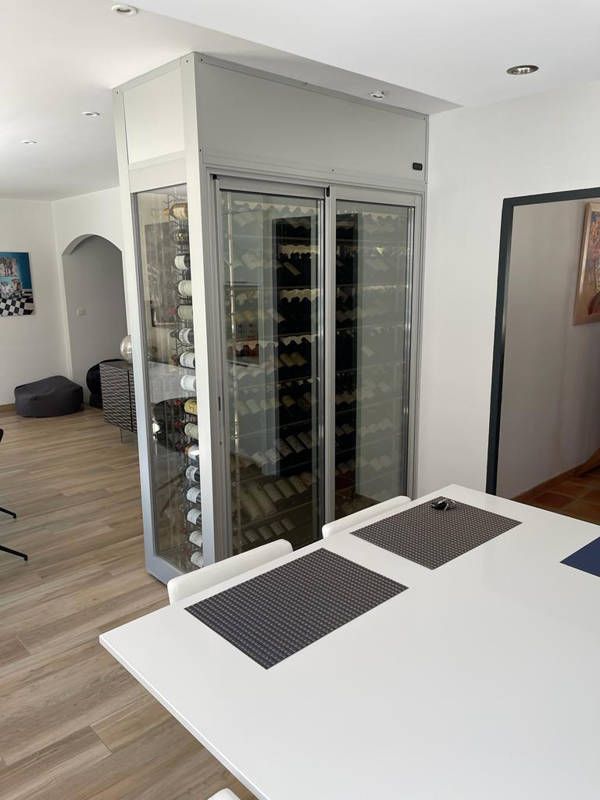 Une cave à vin en séparation murale vitrée chez un particulier dans un salon au murs blanc