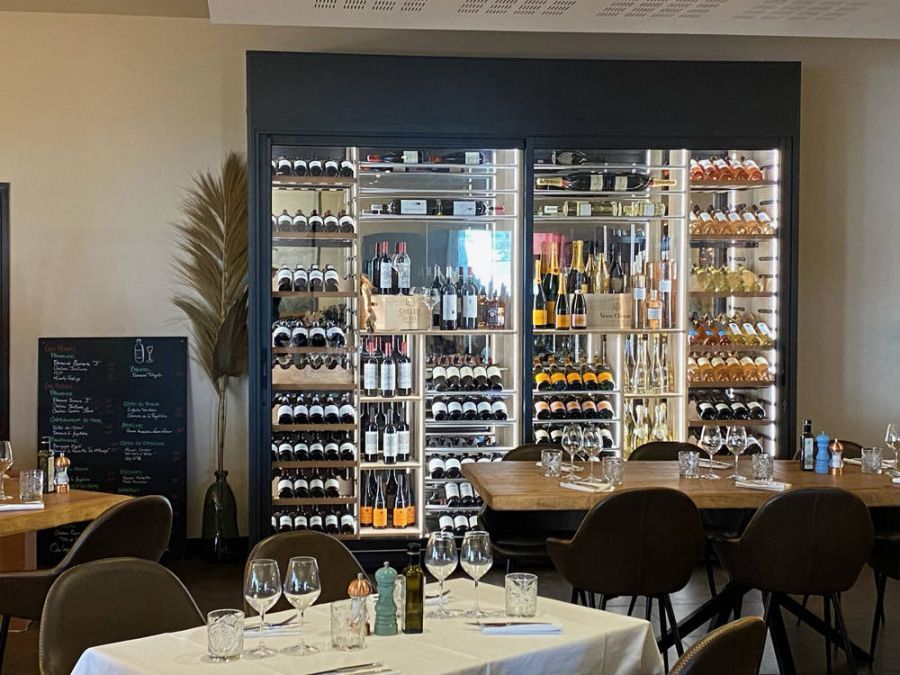 Une cave à vin vitrée et éclairée dans le restaurant les Comédiens
