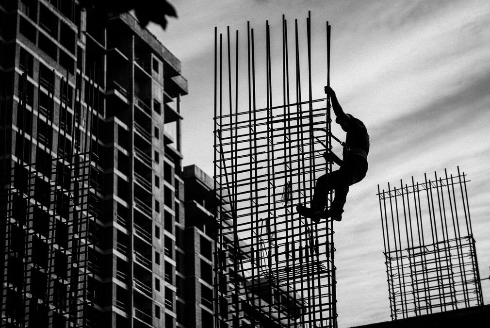Obrero de la construcción trepando por una estructura de varillas de refuerzo
