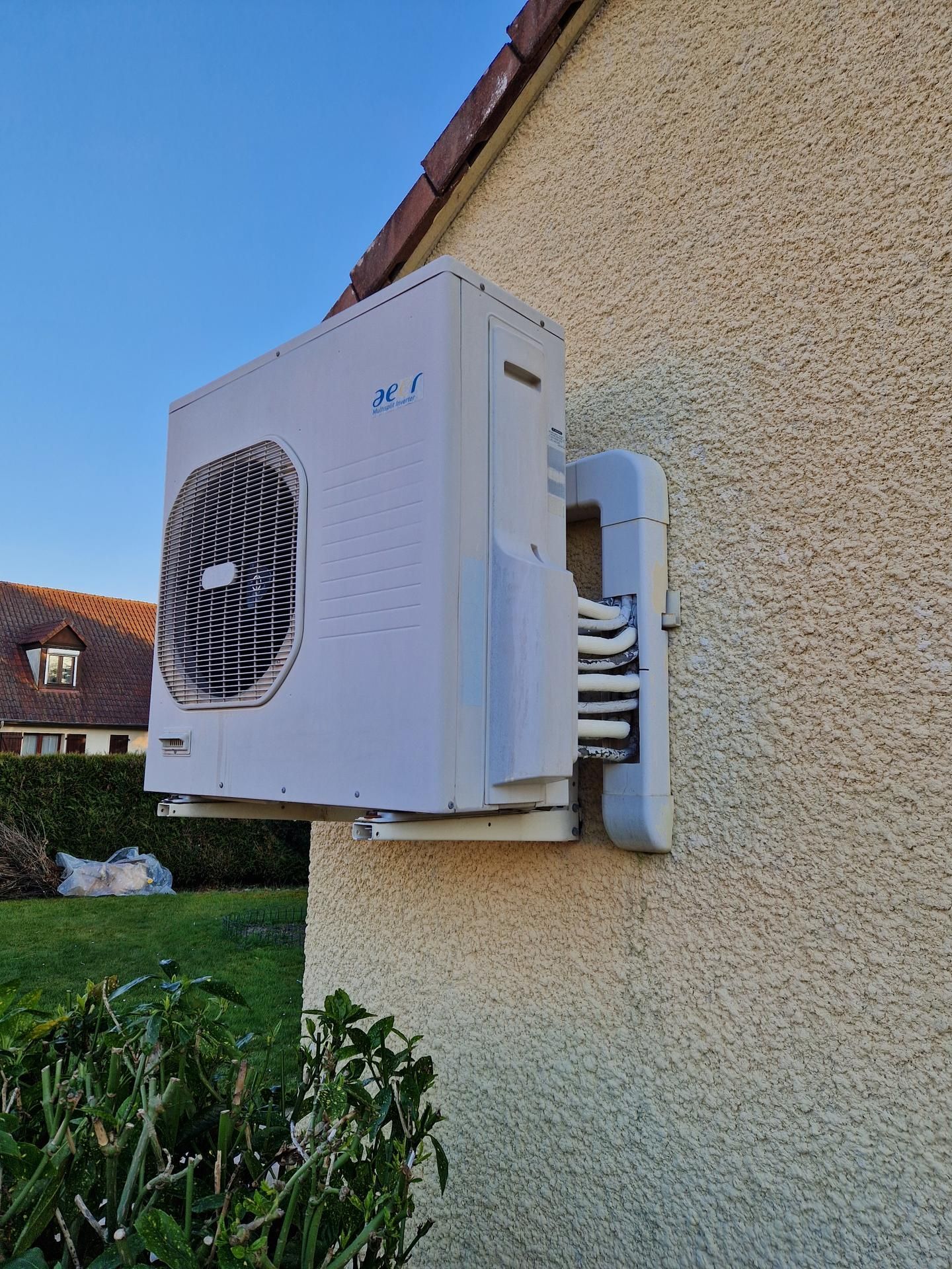 Une unité de pompe à chaleur blanche fixée sur un mur extérieur d'une maison.