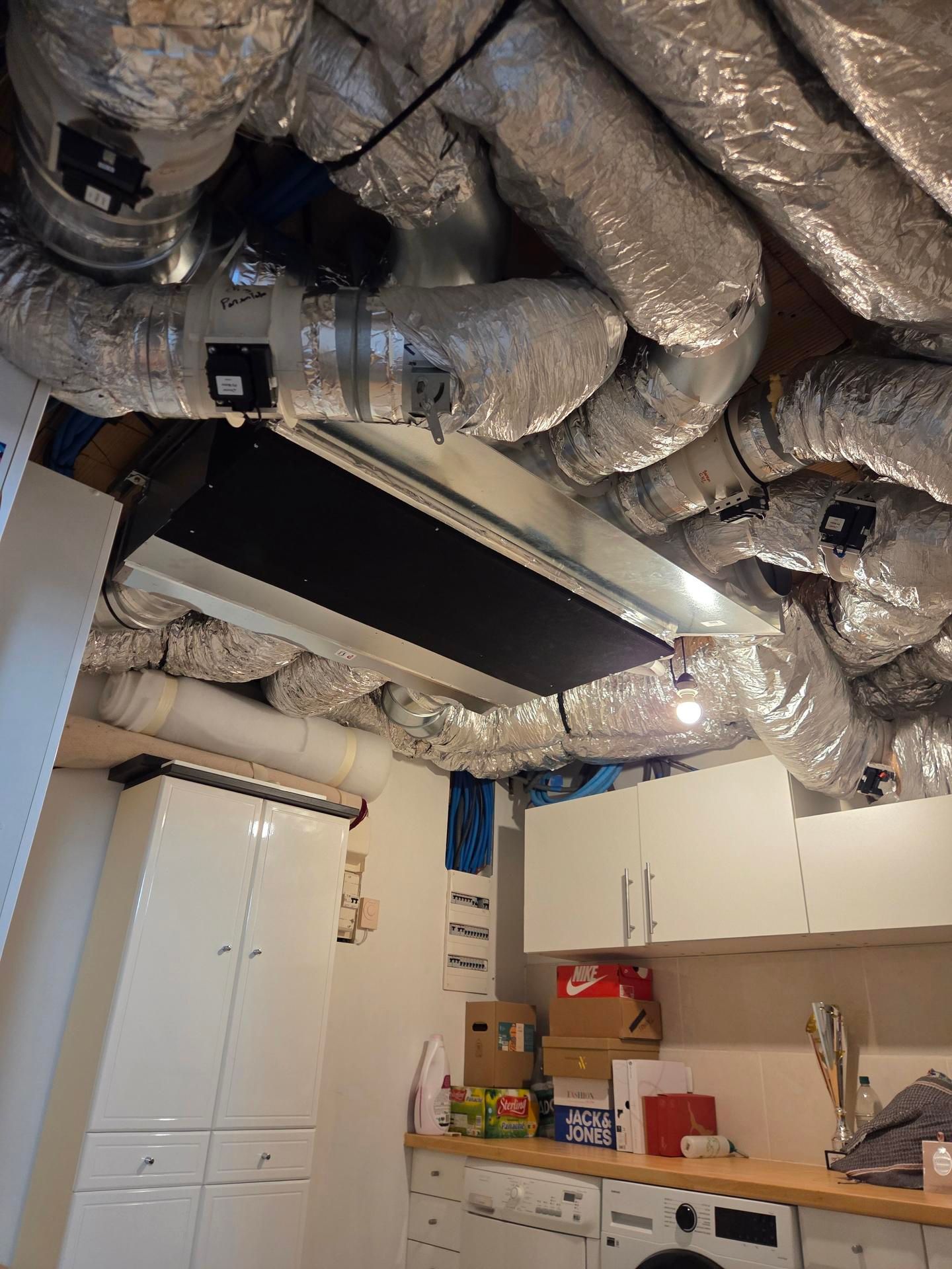 Buanderie avec système de ventilation au plafond, placards blancs et machine à laver.