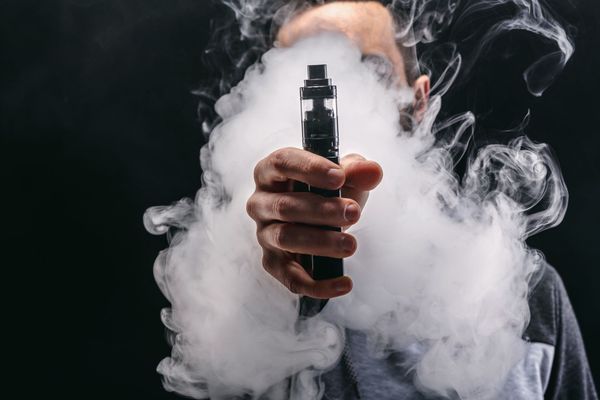 Quelqu'un qui tient une e-cigarette et de la fumée