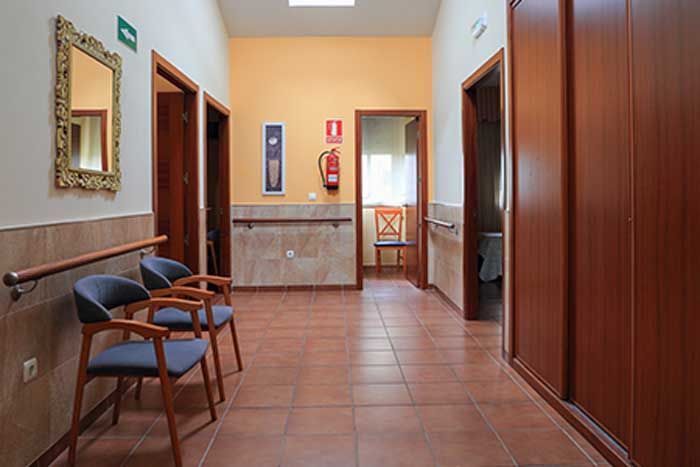 Un pasillo con sillas y un extintor en la pared.
