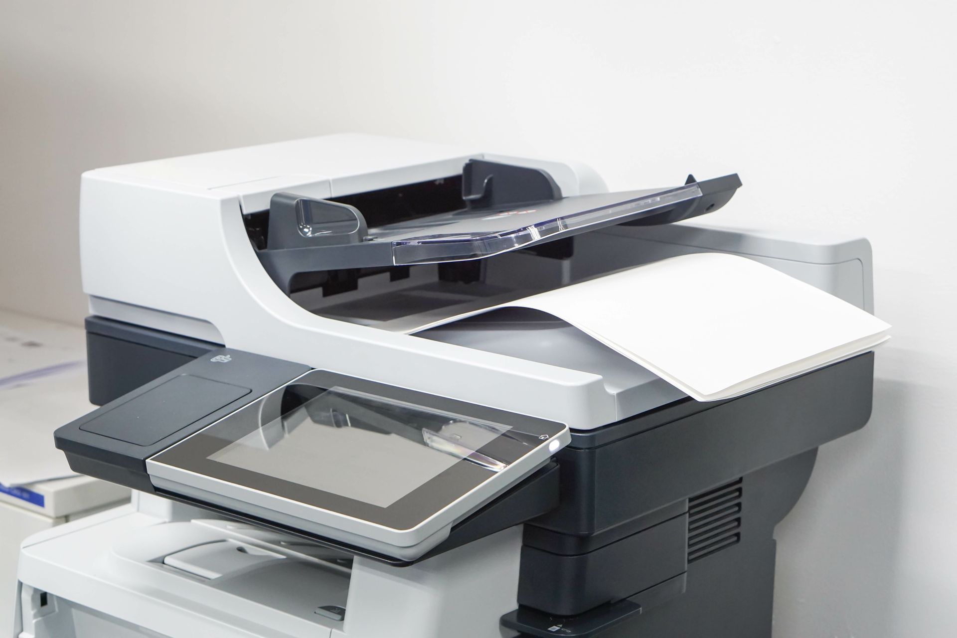 Ein Multifunktionsdrucker mit Touchscreen-Display; weißes Papier wird auf die Scannerfläche gelegt.