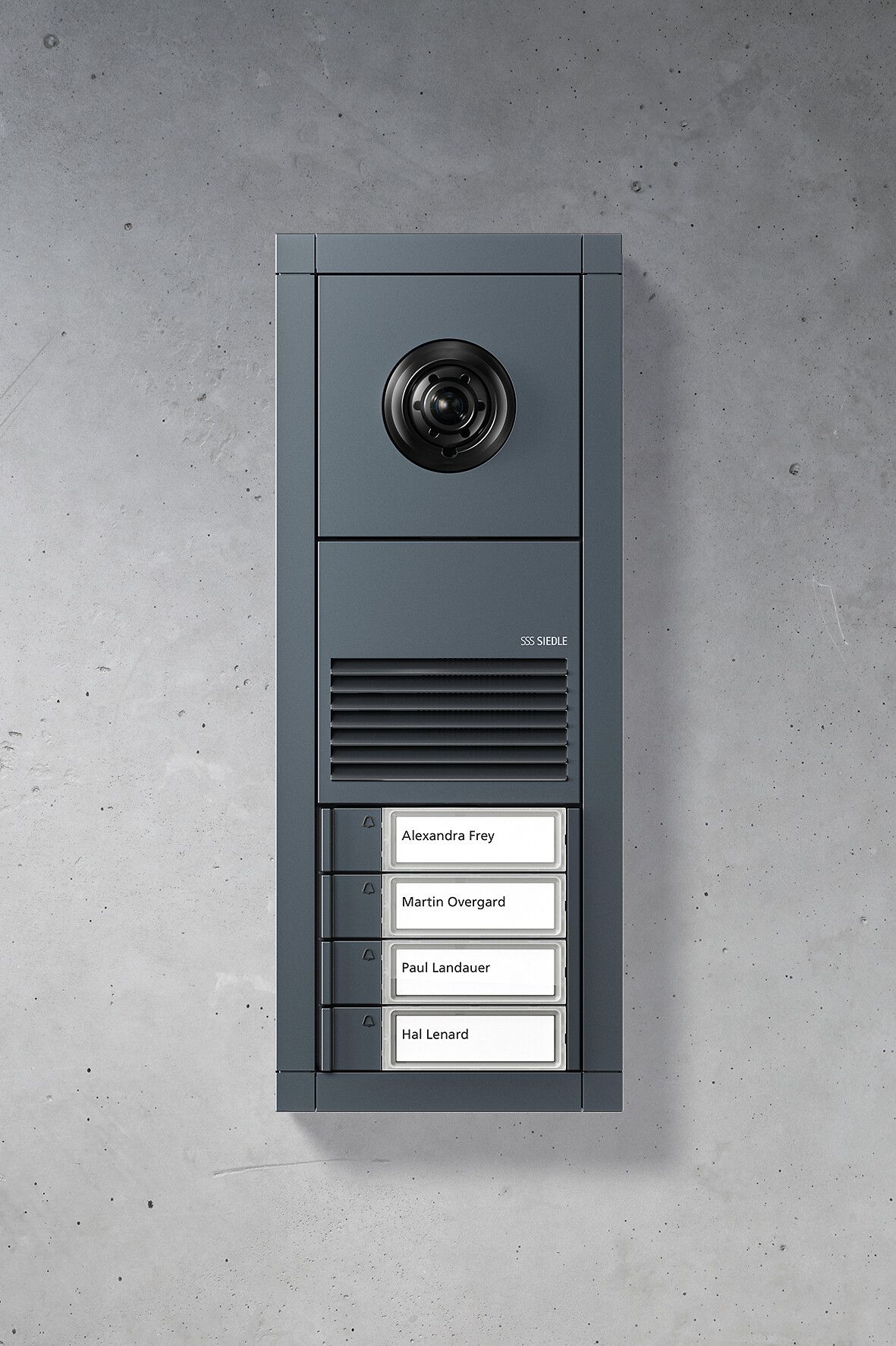 Dunkelgraue Gegensprechanlage an einer Betonwand, mit Kamera, Lautsprecher und Namensschildern.