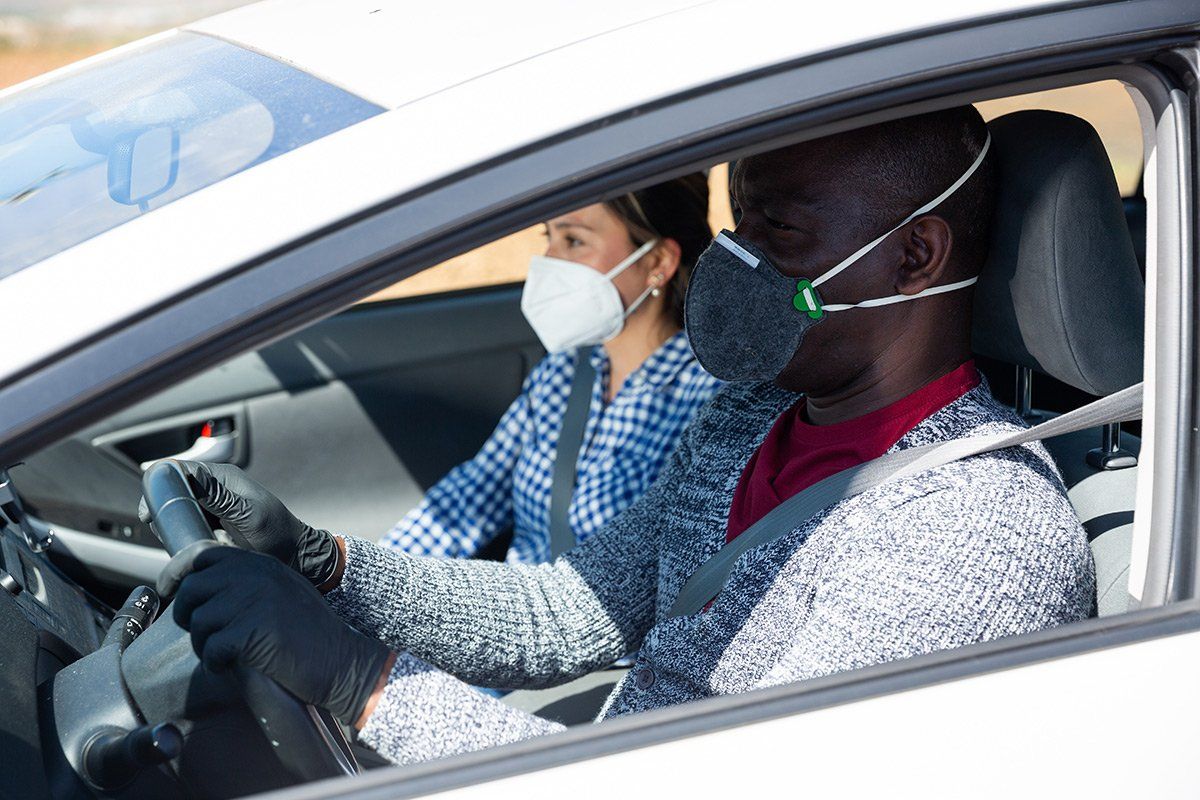 Homme portant un masque au volant de sa voiture conduisant une femme