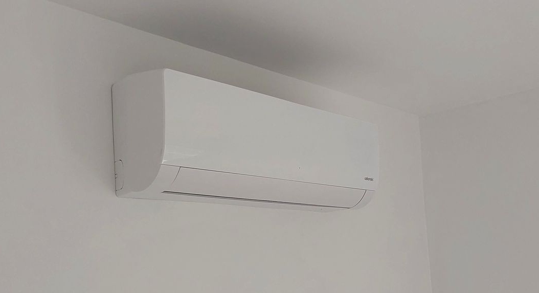 Un climatiseur blanc est fixé au-dessus d'un cadre de porte. Du ruban adhésif rose entoure le cadre de la porte.