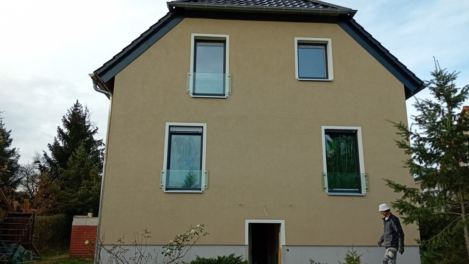 Ein Mann mit Schutzhelm steht vor einem Haus